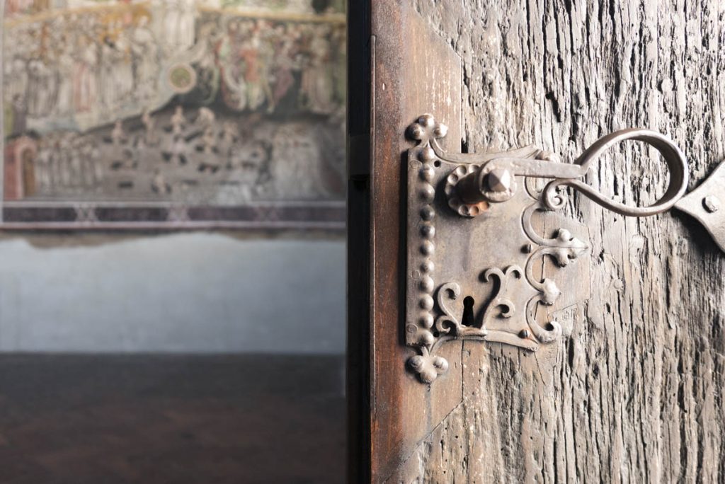 St. Magdalena Kapelle: Der metallene Kranz unter dem Schlüsselloch nennt sich Türschläfer und hilft, das Schlüsselloch zu finden. Bei Dunkelheit. Oder Trunkenheit, könnte man meinen.