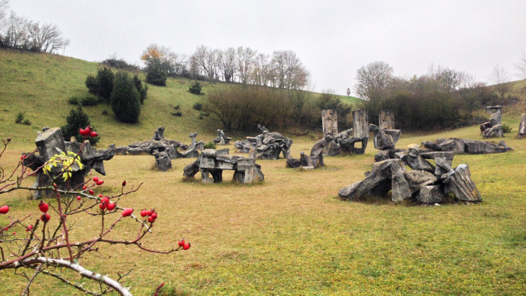 Mehrere Figuren im Figurenfeld Eichstätt im Altmühltal, im Vordergrund ein Hagebuttenstrauch mit Früchten