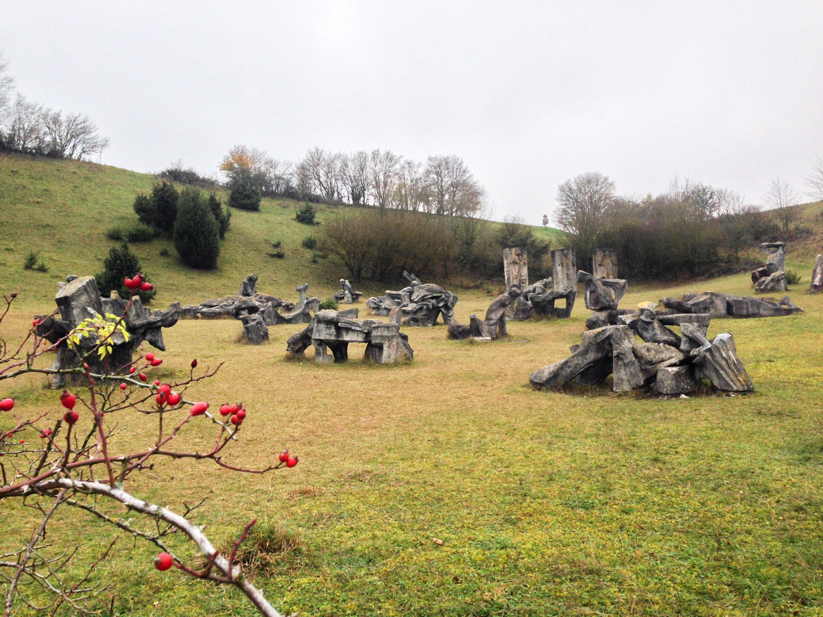 Mehrere Figuren im Figurenfeld Eichstätt im Altmühltal, im Vordergrund ein Hagebuttenstrauch mit Früchten